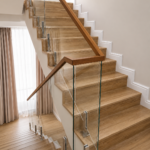Glass staircase balustrade with stainless steel fittings and wooden handrail for a modern villa interior in Dubai by Glass Sea Trading L.L.C.